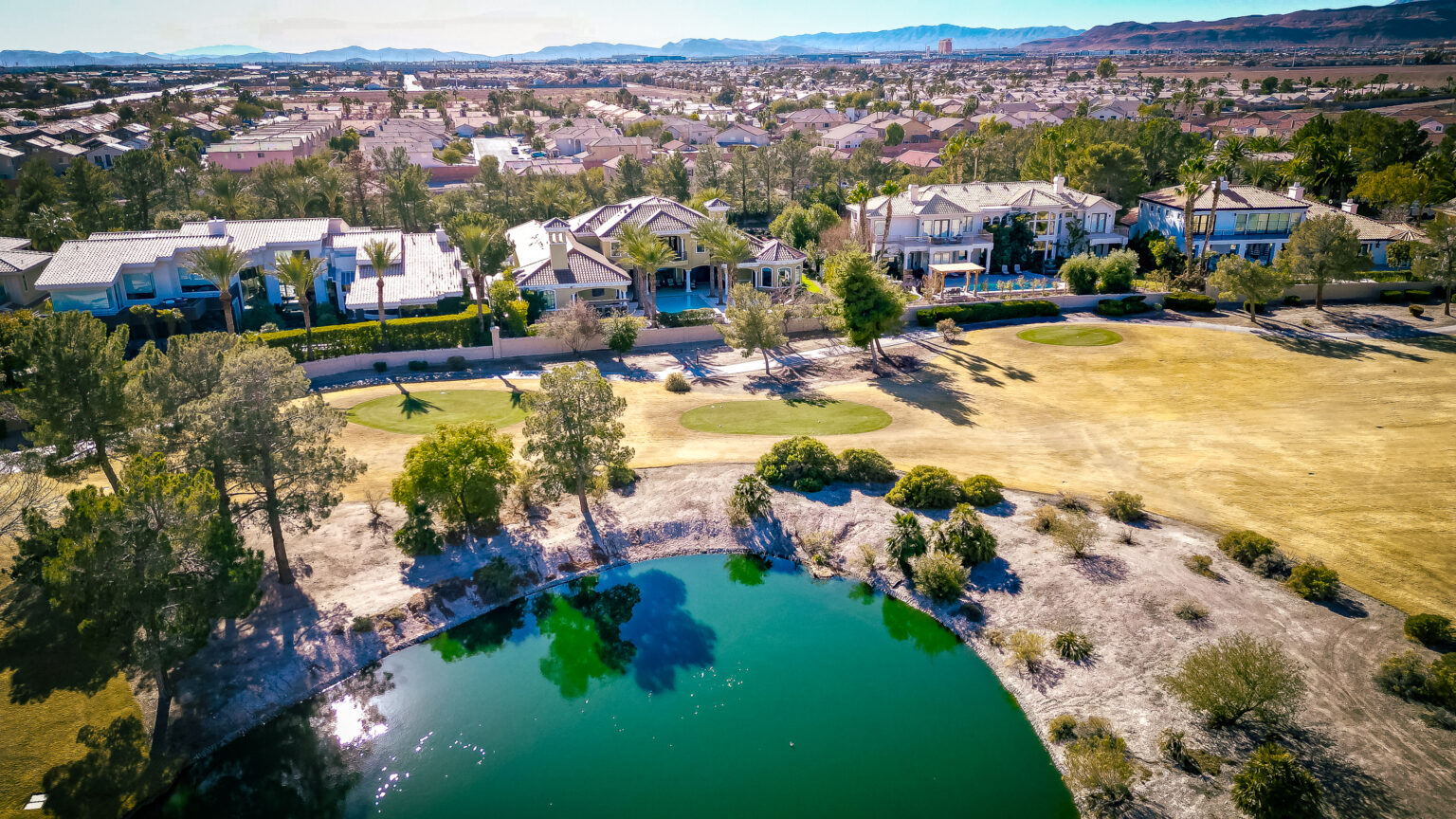 Aerial view of luxury Las Vegas homes around a golf course lake — Award Realty Las Vegas